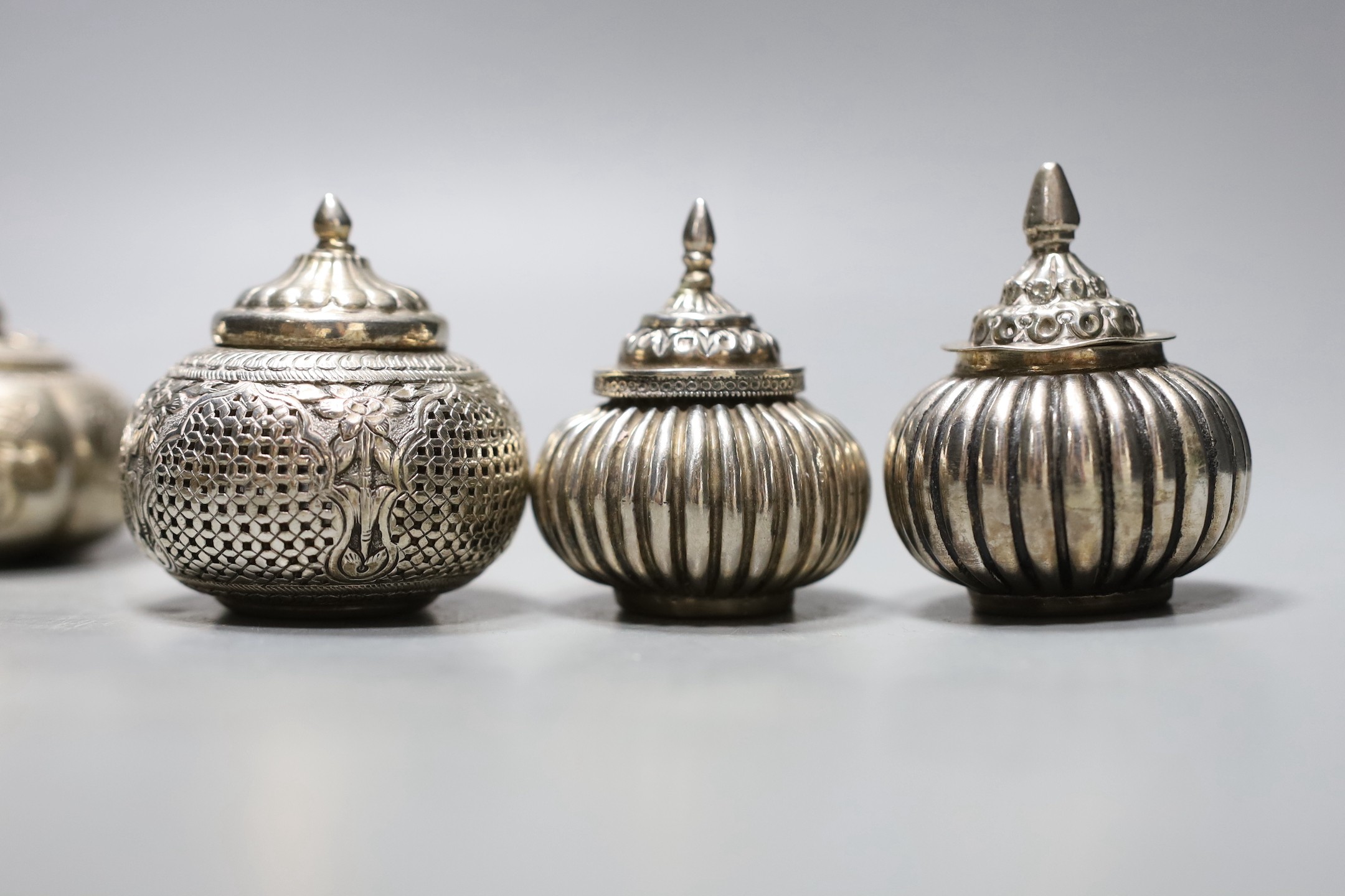 Five assorted 20th century Indian white metal circular boxes and covers including betel nut boxes and one other house shaped box and cover, largest diameter approx. 71mm.